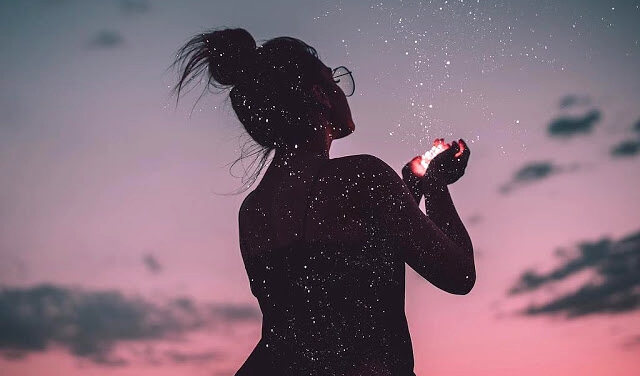 Mujer con luz en la mano representando que la vida se mide en emociones