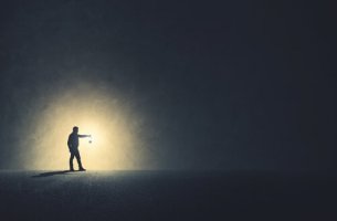 Hombre andando con luz en la oscuridad