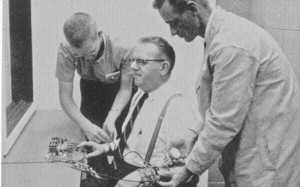 Hombres poniendo aparatos en otro en el experimento de Milgram