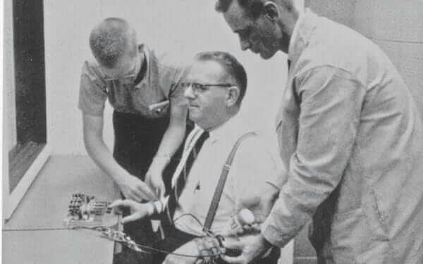 Hombres poniendo aparatos en otro en el experimento de Milgram