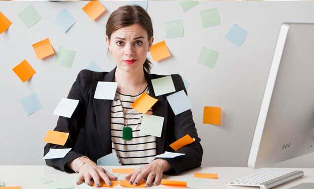 Mujer con estrés crónico rodeada de post-its que piensa en cambiar de trabajo