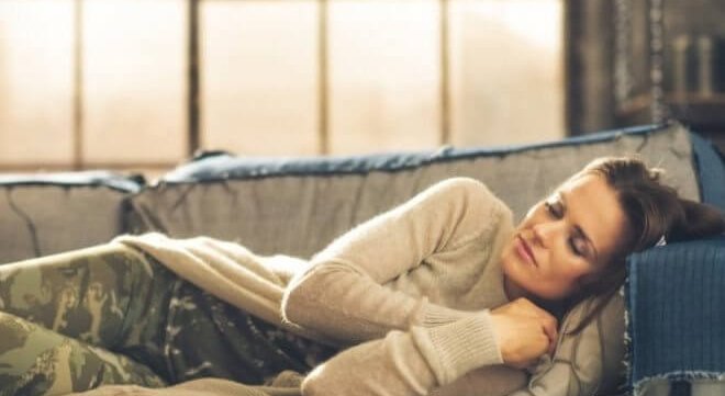 mujer que sufre somniloquia dormida en un sofá 