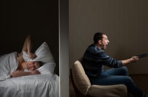 Hombre intentando dormir mientras su vecino hace ruido