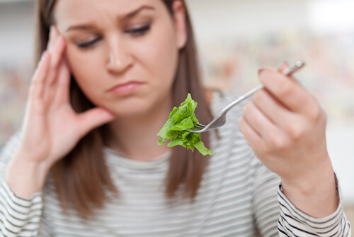 Mujer con ortorexia mirando un trozo de lechuga