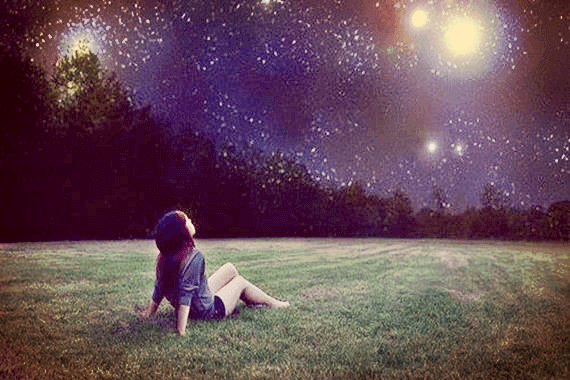 Niña sentada en el césped mirando una estrella