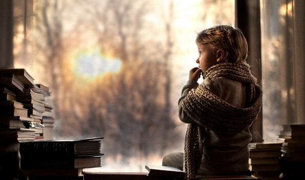 Niño con bufanda mirando por la ventana