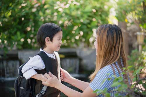 Niño con mochila hablando con su madre sobre el colegio