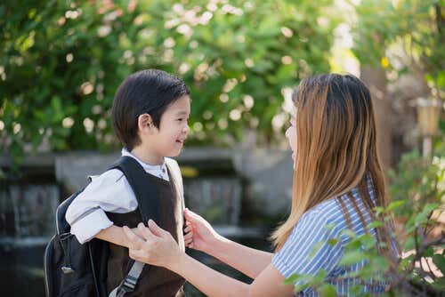 Niño con mochila hablando con su madre sobre el colegio