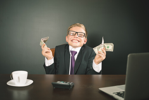 Niño con traje, ordenador y dinero