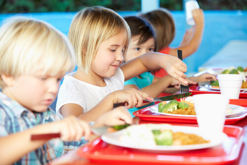 Niños con comida en sus bandejas