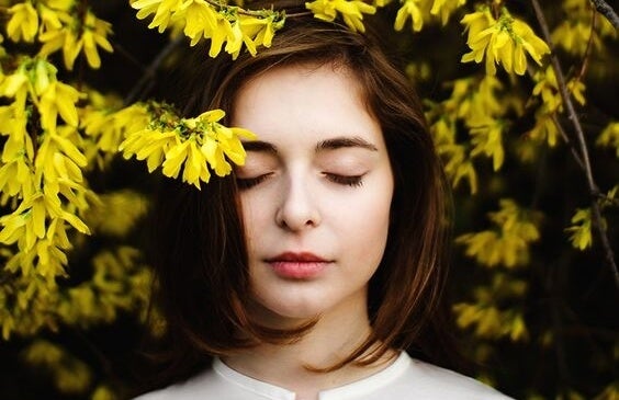 Chica bajo flores amarillas disfrutando de estar bien con uno mismo