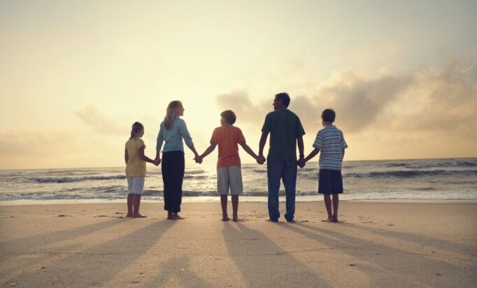 Familia cogida de la mano en la playa