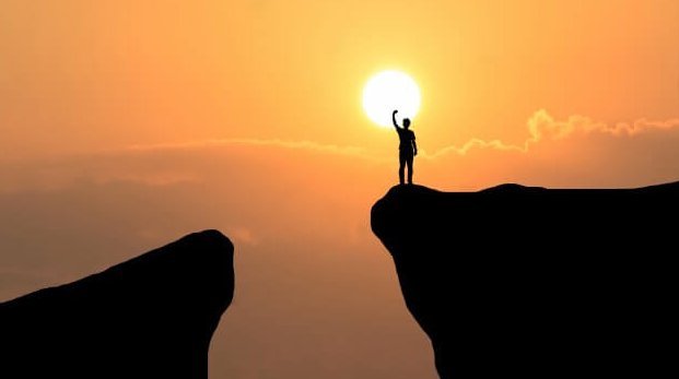 hombre en precipicio tocando sol representando principios de Karl Popper