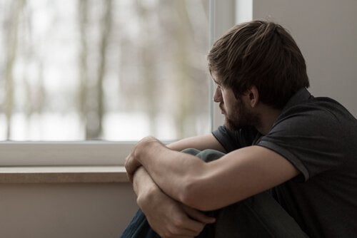 Hombre triste mirando por la ventana pensando en sus problemas para expresar sentimientos
