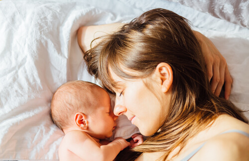 Madre haciendo mimos en la cama a su bebé