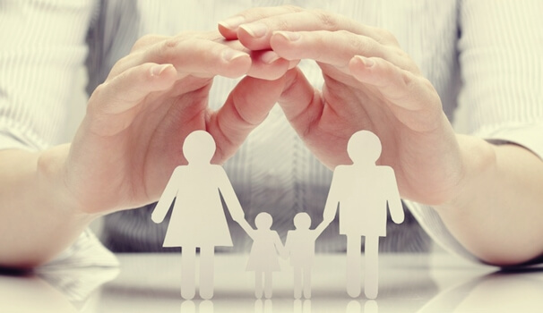 Manos sobre una familia de papel para representar la adopción