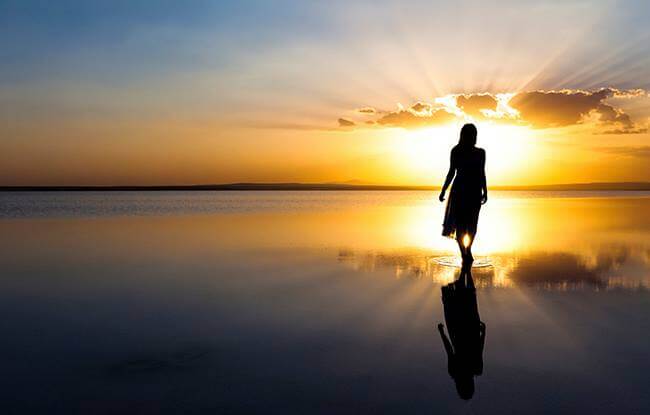 mujer avanzando por playa representando las frases para recuperar la energía positiva