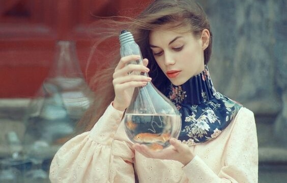 chica mirando bombilla donde hay un pez pensando en las leyes de las emociones