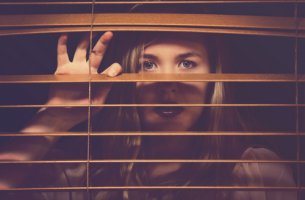 Mujer con indefensión aprendida mirando detrás de una ventana