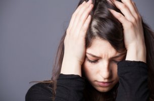 Mujer con trastorno mixto ansioso-depresivo con manos en la cabeza