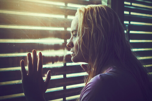 Mujer mirando por la ventana como símbolo de la pregunta qué hacer con tu vida