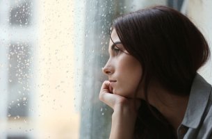 Mujer preocupada mirando por la ventana