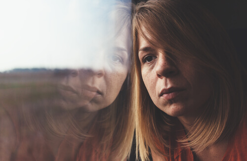 Mujer triste apoyada en una ventana