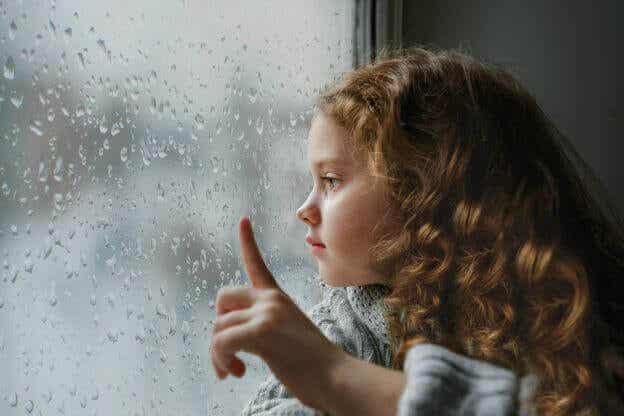 En liten jente ser ut av vinduet,
