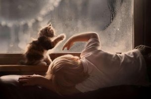 Niño con autismo mirando por la ventana junto a su gato