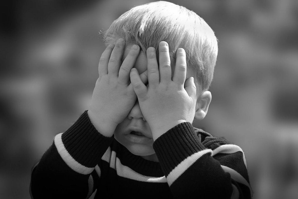 Niño con las manos sobre los ojos para representar el estrés infantil