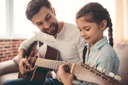 Padre enseñando a su hija a tocar la guitarra