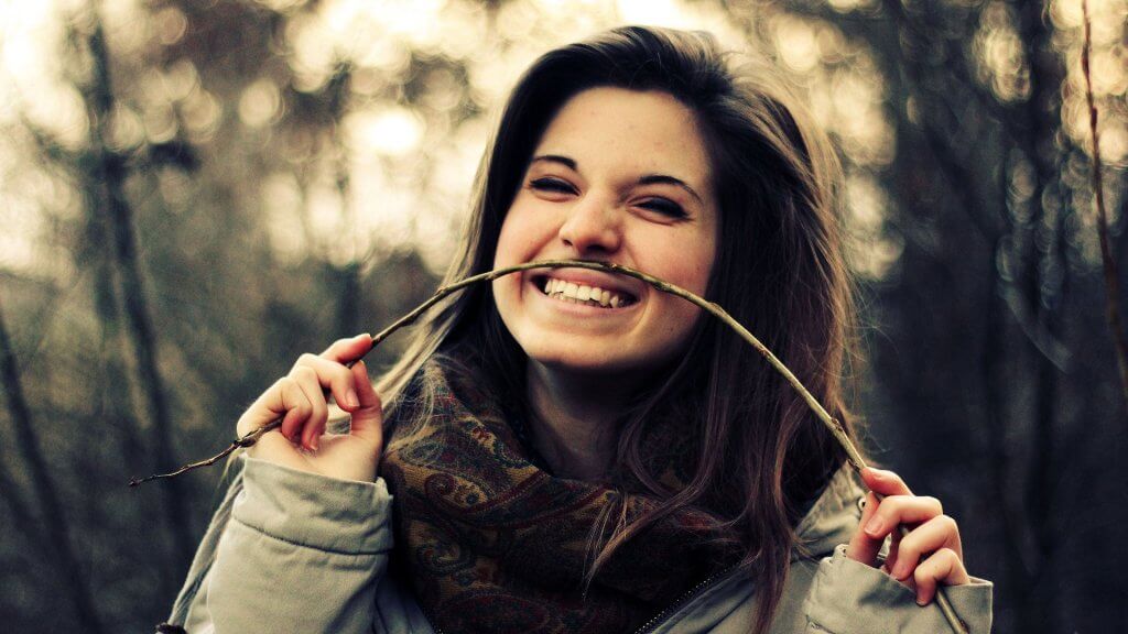 Chica sonriendo con rama de árbol