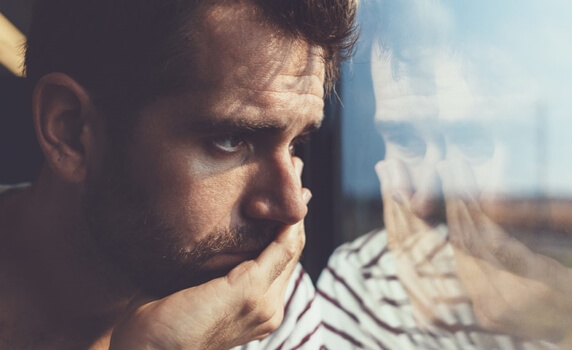 Hombre triste ante un cristal