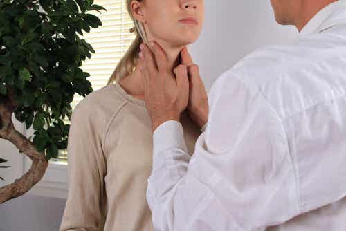 Médico palpando la tiroides de su paciente para representar la relación entre estrés e hipertiroidismo
