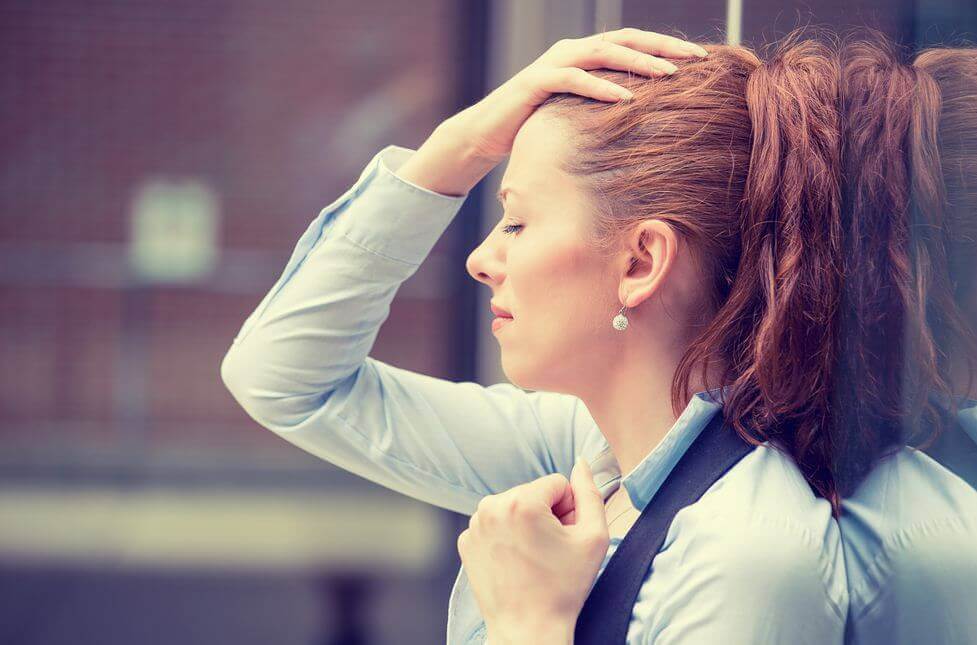 Mujer con la mano en la cabeza porque se siente quemada en el trabajo