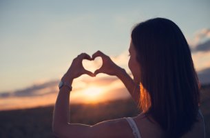 Mujer haciendo con sus manos la forma de un corazón