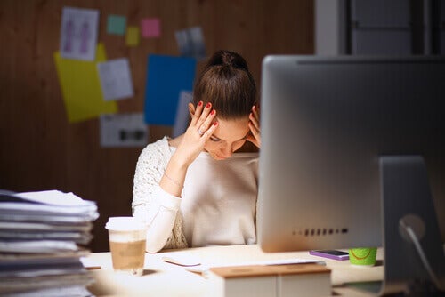 Mujer joven con burnout delante de su escritorio