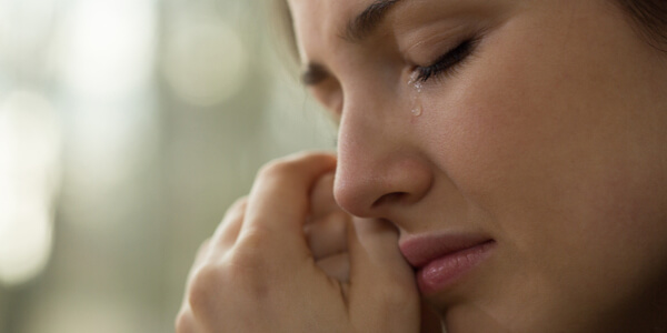 Mujer llorando y secándose sus lágrimas en su habitación