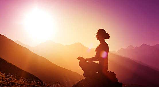Mujer meditando en una montaña al amanecer