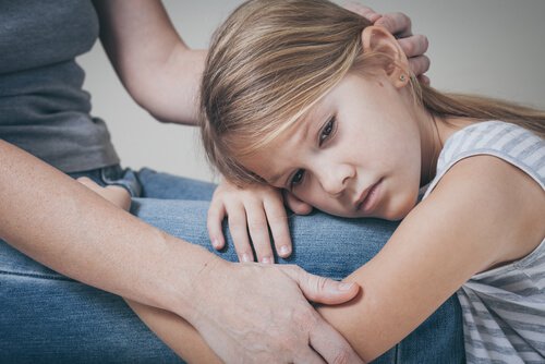 Niña triste agarrada a su madre