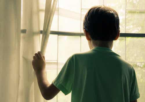 Niño con discapacidad intelectual mirando por la ventana
