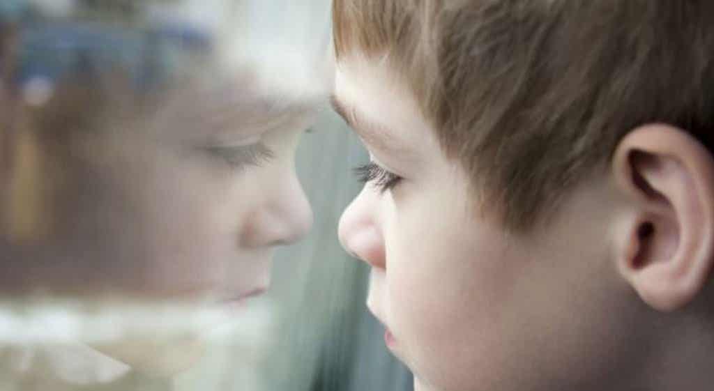 Niño mirando tras un cristal representando las futuras causas del narcisismo exagerado