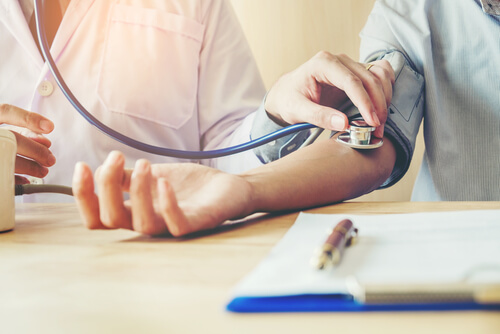 Médico tomando presión arterial a su paciente