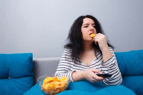 Mujer comiendo patatas mientras ve la televisión
