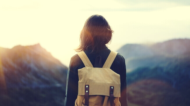 Mujer con mochila ante una montaña