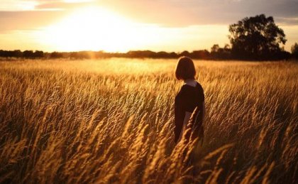 Mujer en un campo de trigo viendo el atardecer