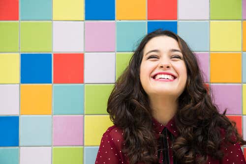 Smilende kvinde foran farverig væg