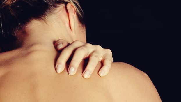 Mujer tocándose la espalda debido a el trastorno por excoriación