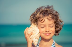 Niña escuchando una caracola