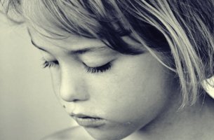 Niña triste con los ojos cerrados al sufrir el robo de la infancia